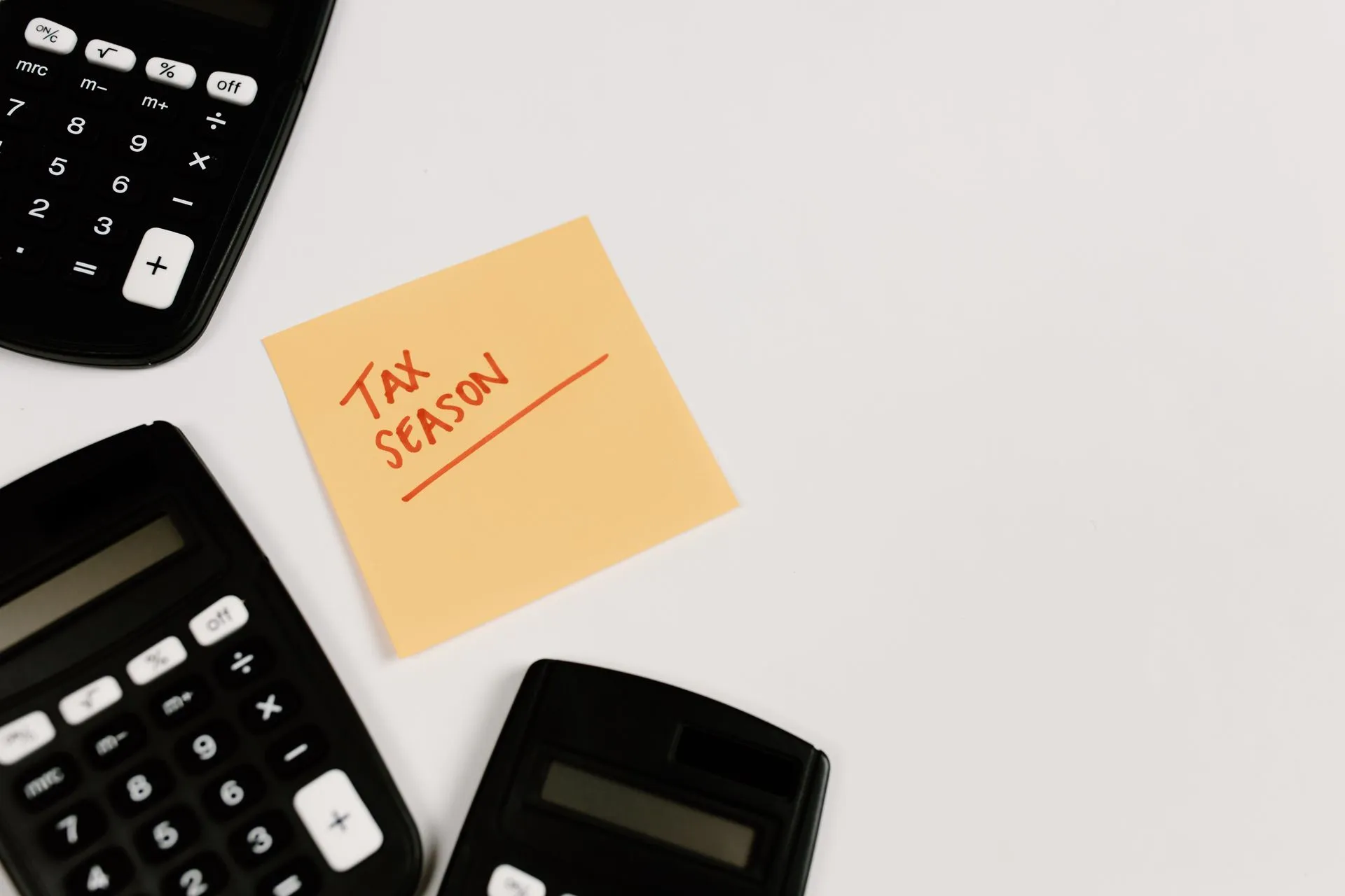 Calculators and sticky note labeled 'Tax Season' on white background, ideal for financial themes, illustrating ShinyHunters renews PeopleSoft attacks as data theft extortion spreads
